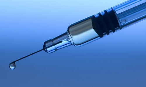 A fluid drop is dispensed from a medical syringe.